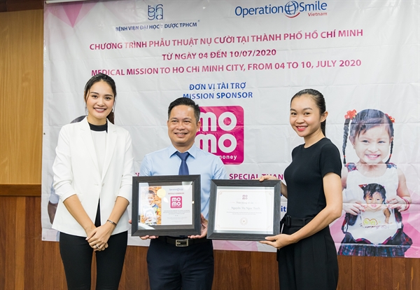Bà Trần Hương Giang - Quản lý phát triển Operation Smile Việt Nam trao bằng lưu niệm đến Đại diện Ví MoMo, đặc biệt là chị Nguyễn Thị Ngọc Tuyết - người dùng Ví MoMo có số lượng Heo Vàng quyên góp nhiều nhất.