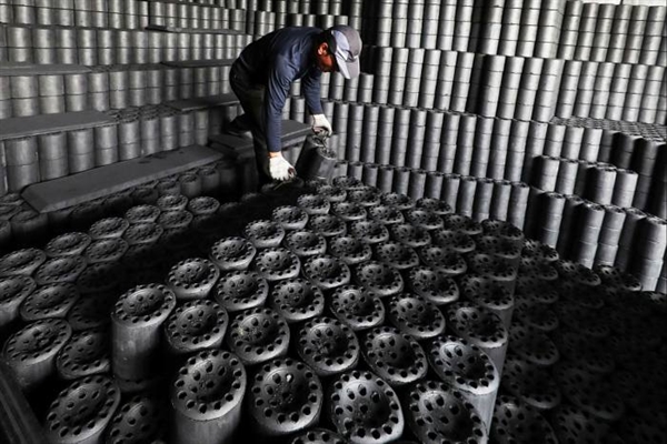 Một công nhân chất những viên than lên xe tải tại một nhà máy ở Hwaseong, phía nam Seoul. Ảnh: EPA.