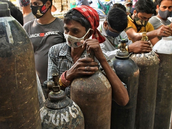 Người dân xếp hàng để nạp đầy bình oxy cho những người bị nhiễm COVID-19 tại các cơ sở y tế quá tải ở New Delhi. Ảnh: AP.