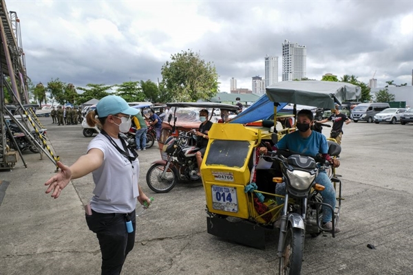 Một nhân viên y tế hướng dẫn một tài xế xe ôm tại điểm tiêm chủng COVID-19 ở Manila, Philippines, vào ngày 22.6. Ảnh: Bloomberg.