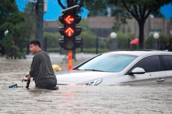 Một người đàn ông đi xe đạp qua một ngã tư ngập lụt ở Trịnh Châu ngày 20.7.2021. Ảnh: AP.
