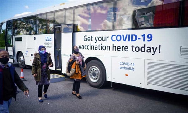 Mọi người rời khỏi xe buýt tiêm chủng di động sau khi nhận vaccine COVID-19 tại Học viện ESSA ở Bolton, Anh. Ảnh: The Guardian.