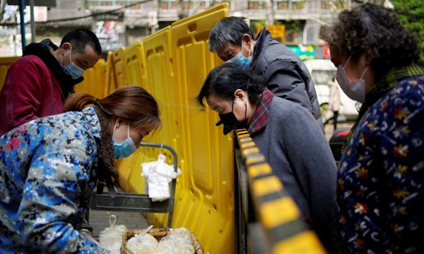 Người dân nhận đồ ăn tại một khu phố bị phong tỏa ở Vũ Hán, tỉnh Hồ Bắc, Trung Quốc, hồi tháng 4/2020. Ảnh: Reuters.