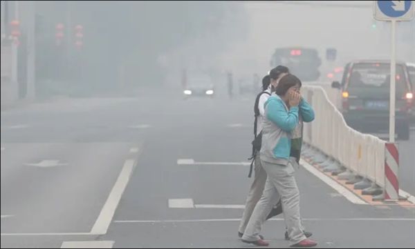 Người đi bộ che mặt khi băng qua đường ở Bắc Kinh trong khói bụi dày đặc năm 2015. Ảnh: AFP.