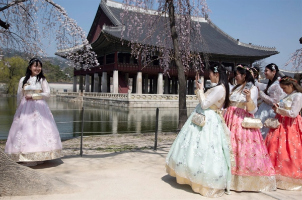 Du khách mặc trang phục truyền thống của Hàn Quốc và chụp ảnh trong chuyến thăm Cung điện Gyeongbokgung ở Seoul, Hàn Quốc. Ảnh: EPA-EFE
