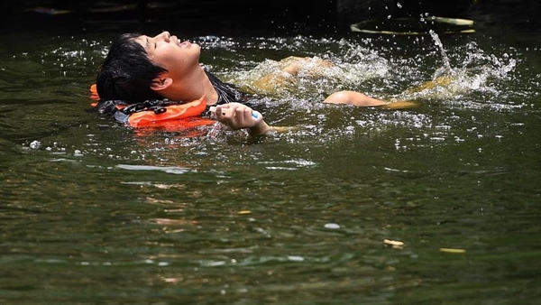 Một người đàn ông bơi trong một con kênh khi nhiệt độ đạt mức kỷ lục 45,4 độ C (113,7 độ F) ở Bangkok, Thái Lan, 
