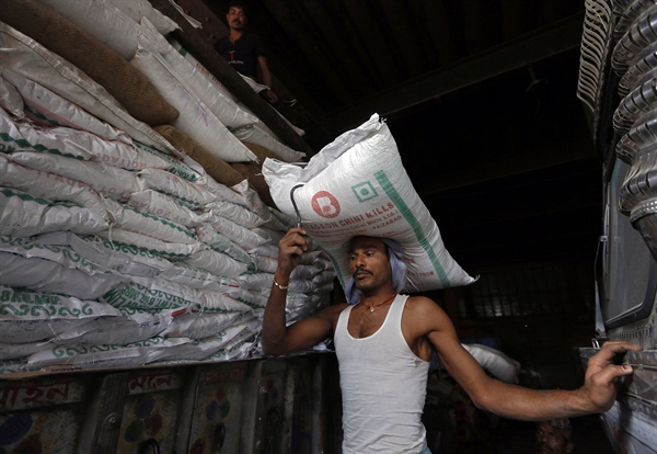 Một người lao động mang bao đường để chất lên xe tải cung cấp tại khu chợ ở Kolkata, Ấn Độ,