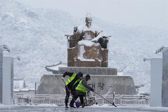 công nhân đang dọn tuyết trước bức tượng Vua Sejong tại Quảng trường Gwanghwamun ở Seoul sau khi có tới 26 cm tuyết rơi xuống thành phố chỉ trong một ngày. ( AP: Ahn Young-joon )