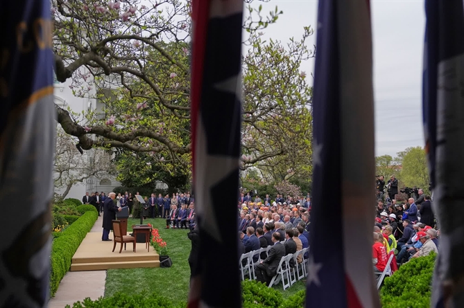 Trump thông báo các mức thuế mới tại Vườn Hồng Nhà Trắng vào ngày 2 tháng 4. Tổng thống đã nhiều lần nhấn mạnh rằng thuế quan là cách giúp chính phủ Mỹ giảm bớt sự phụ thuộc vào thuế thu nhập như một nguồn thu chính. Tuy nhiên, các nhà kinh tế học phần lớn đều đồng ý rằng thuế quan do nước nhập khẩu hàng hóa chi trả và lịch sử cho thấy thuế quan thường dẫn đến giá cả cao hơn cho người tiêu dùng. (Evan Vucci/AP)