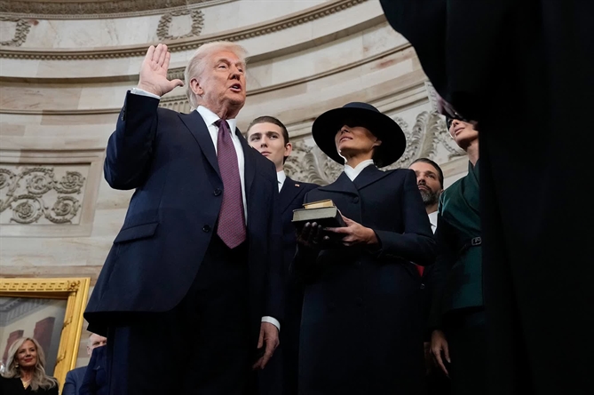 Trump tuyên thệ nhậm chức tổng thống thứ 47 của Hoa Kỳ dưới sự chủ trì của Chánh án Tòa án Tối cao John Roberts. Đệ nhất phu nhân Melania Trump cầm Kinh Thánh trong buổi lễ. Lễ nhậm chức của Trump đã được chuyển vào tổ chức trong nhà do dự báo thời tiết ở thủ đô Washington quá lạnh, gây nguy hiểm. Ảnh: AP