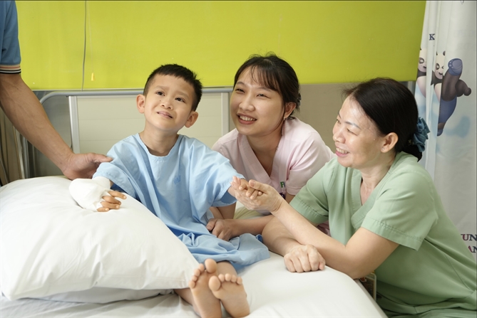 Bé Duy Quang sau khi được phẫu thuật tay phải, đặt bộ khung để kéo xương. Ảnh: FV