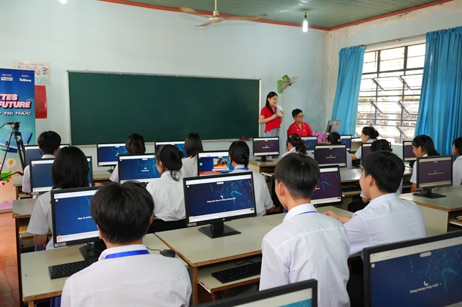 Các em học sinh trường THPT Nguyễn Huệ A và tình nguyện viên Keppel tham gia một trò chơi giáo dục trên máy tính do Keppel trao tặng tại chương trình Bytes for Future.