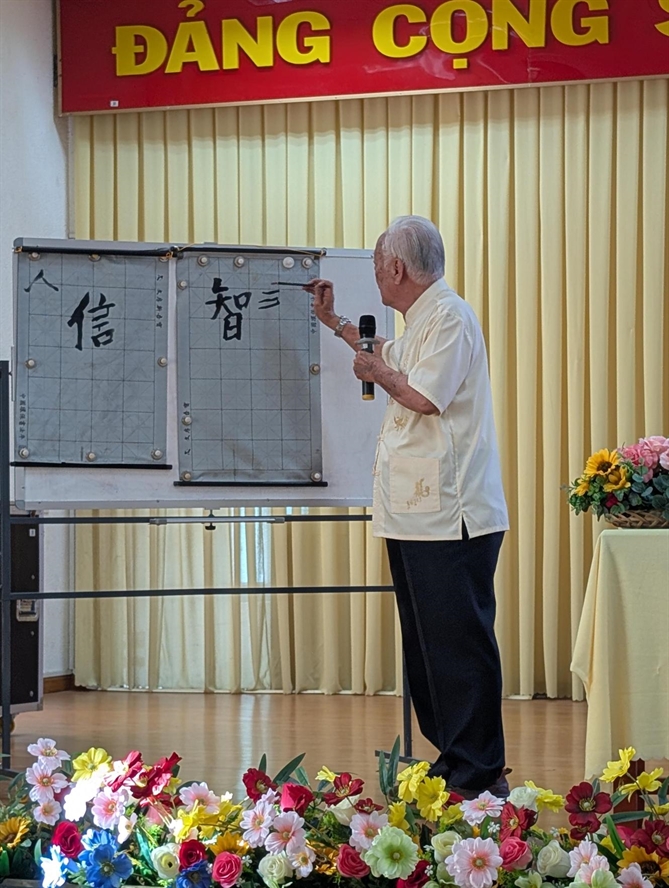 Nhà thư pháp Ô Dân Phát đang trình diễn thư pháp tại Trường Đại học Trà Vinh